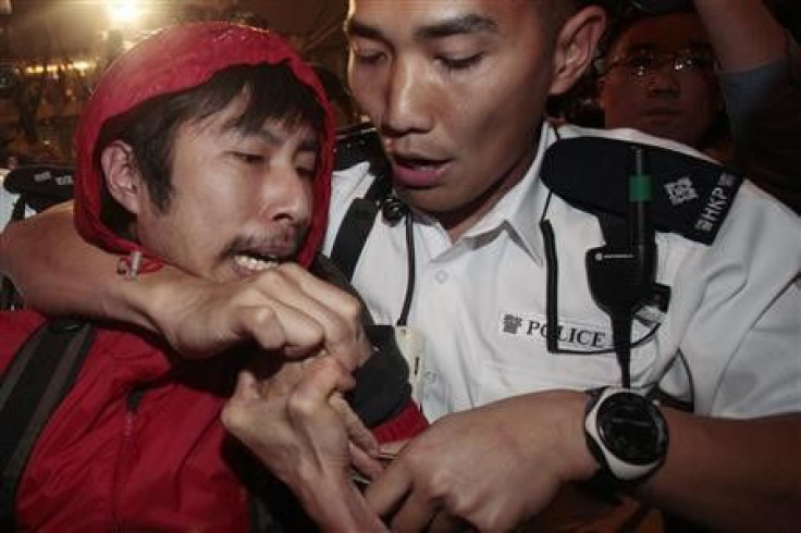 Policemen remove a protester during a sit in protest against the annual budget along Des Voeux Road in Hong Kong