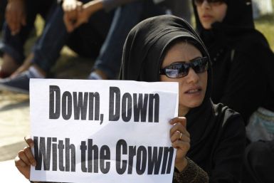 A female anti-government protester holds a banner during a protest at the Bahrain Financial Habour in Manama