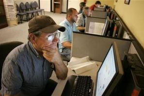 Stephen Battaglia (L) of West Palm Beach, Florida searches for jobs on a computer at Workforce Alliance in West Palm Beach