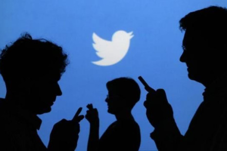 people-holding-mobile-phones-are-silhouetted-against-backdrop-projected-twitter-logo