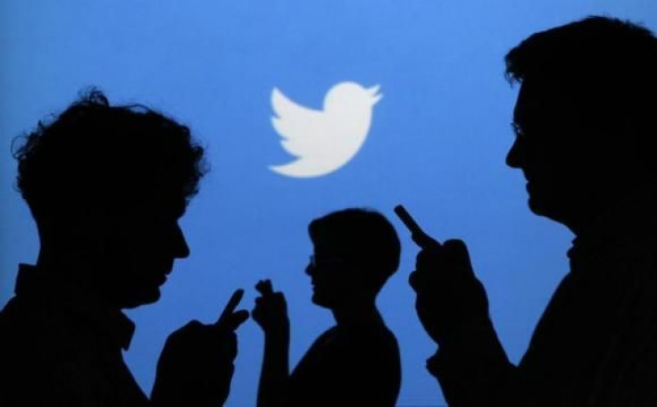 people-holding-mobile-phones-are-silhouetted-against-backdrop-projected-twitter-logo