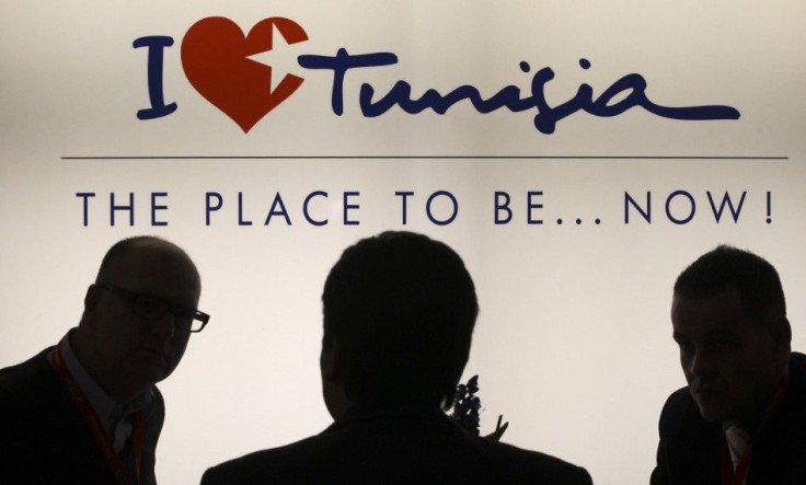 Visitors are silhouetted against a back-lit advertising campaign panel at booth of Tunisia at the international tourism industry fair in Berlin