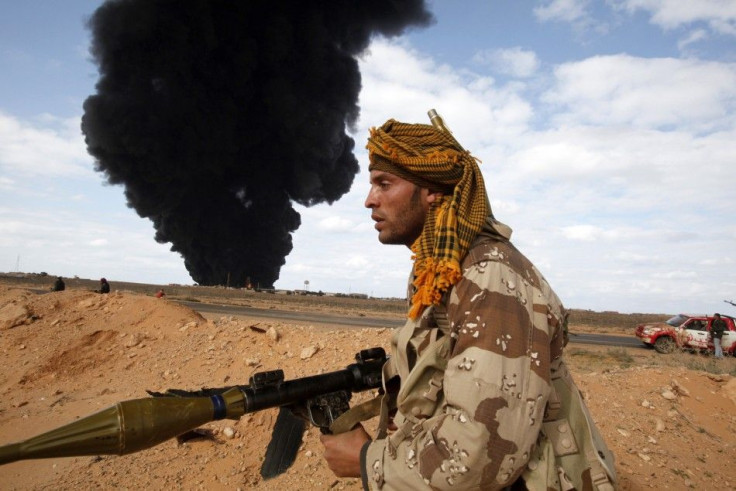 A rebel walks with his rocket propelled grenade launcher during clashes with pro-Gaddafi forces between Ras Lanuf and Bin Jawad