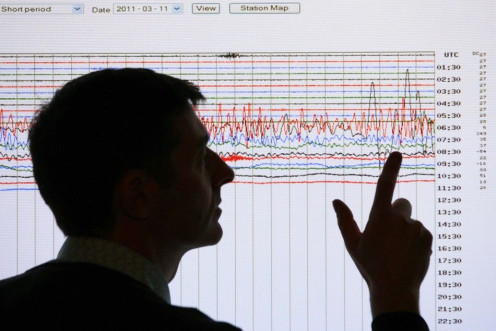 A seismologist poses points to a seismographic graph showing the magnitude of the earthquake in Japan, on a monitor at the British Geological Survey office in Edinburgh