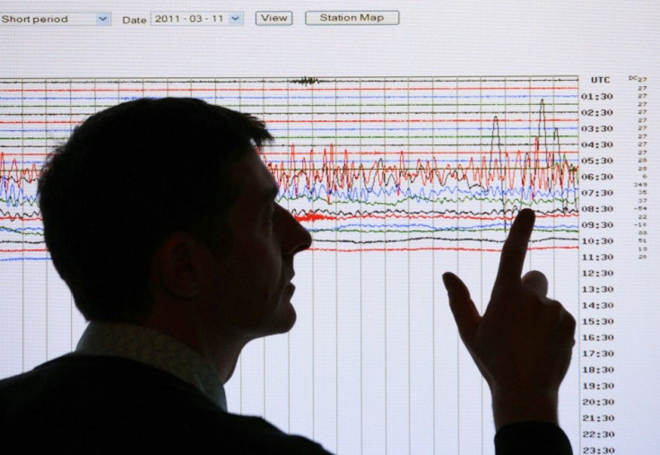 A seismologist poses points to a seismographic graph showing the magnitude of the earthquake in Japan, on a monitor at the British Geological Survey office in Edinburgh