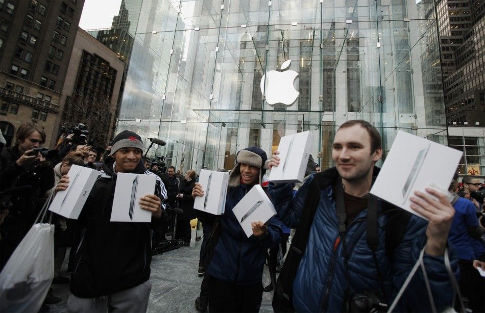 Customers hold up their Apples iPad 2 tablets after purchasing the second generation devices at the Apples flagship 5th Ave store in New York