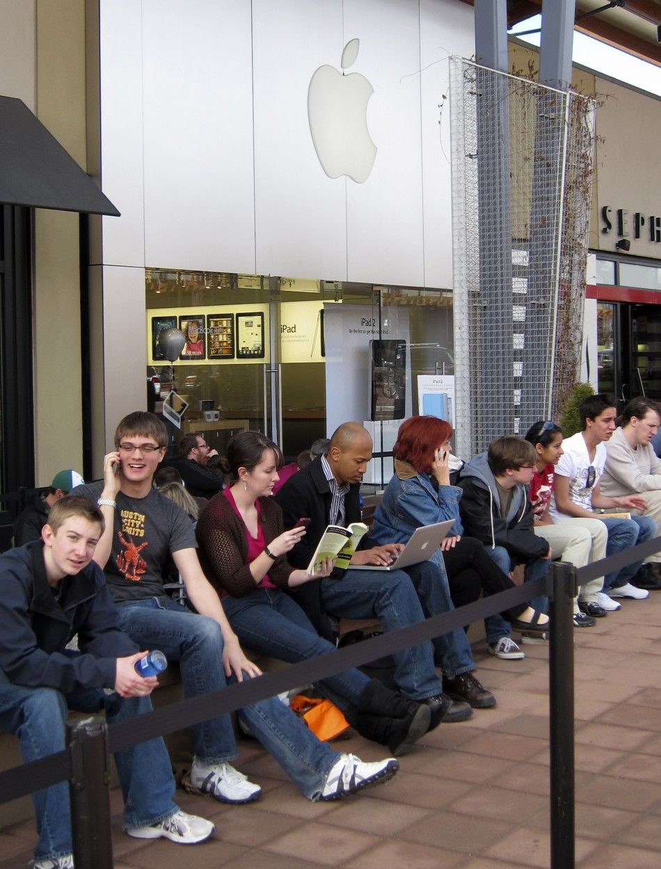 People look at their phones and computers as they wait for the iPad 2 to go on sale at the Apple store in Boulder