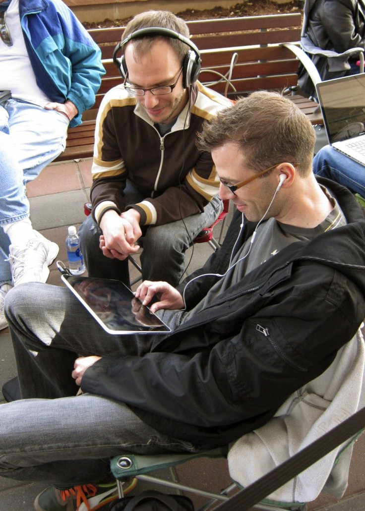 Two men watch a movie on an iPad as they wait outside the Apple store for the sale of the iPad 2 in Boulder