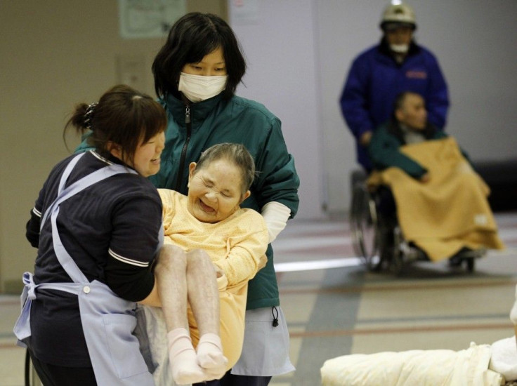 Caretakers carry a woman who is evacuated from a nursing home, which is located in the evacuation area near the Fukushima Daini nuclear plant, at a temporary shelter in Koriyama