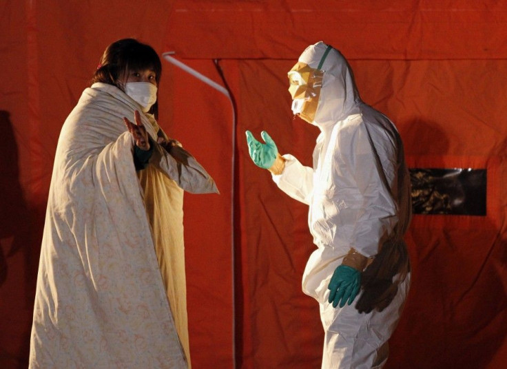 Official in protective gear talks to a woman who is from the evacuation area near the Fukushima Daini nuclear plant in Koriyama