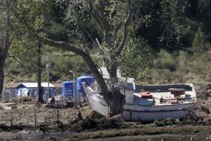 A damaged boat is seen after being dragged onto dry land by a tsunami which hit a small bay of Coliumo 