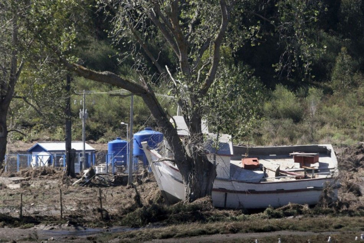 A damaged boat is seen after being dragged onto dry land by a tsunami which hit a small bay of Coliumo 