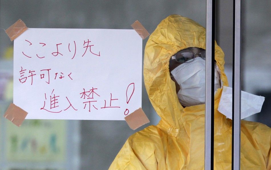 A technician in protective gear looks out of a window at a makeshift facility to screen, cleanse and isolate people with high radiation levels in Nihonmatsu, northern Japan