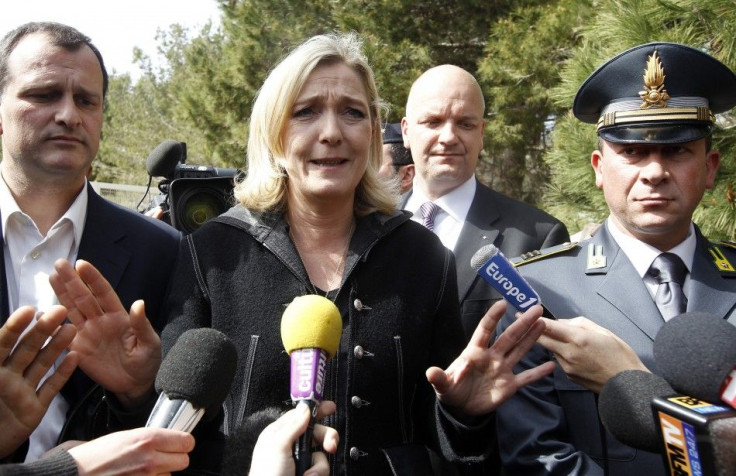Marine Le Pen gestures as she talks with reporters before visiting the immigration centre at the Italian Island of Lampedusa