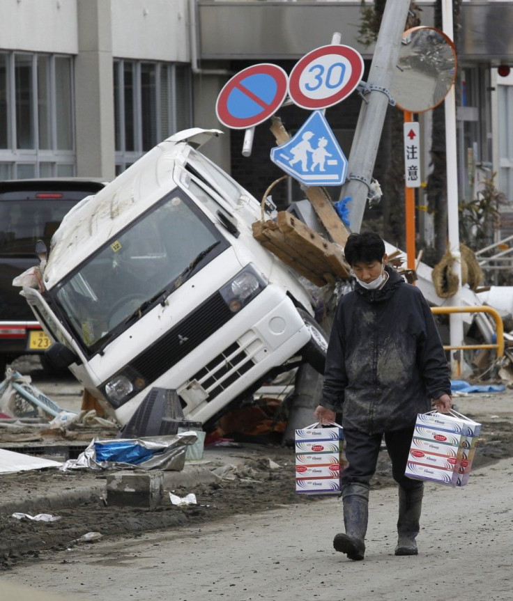 A man carries boxes of tissue papers at a devastated area hit by earthquake and tsunami in Kesennuma, Miyagi Prefecture in northern Japan, March 15, 2011