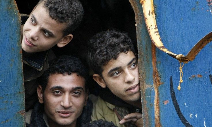 Would-be immigrants look out of a window from a fishing ship 