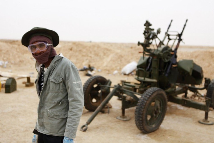 A Libyan rebel stands near an anti-aircraft gun at a checkpoint outside the city of Ajdabiyah
