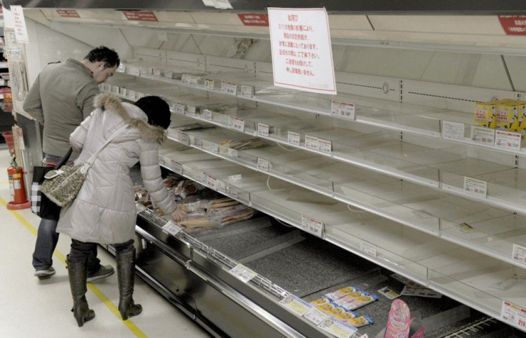 People shop for food from an almost empty shelf at a store in Tokyo