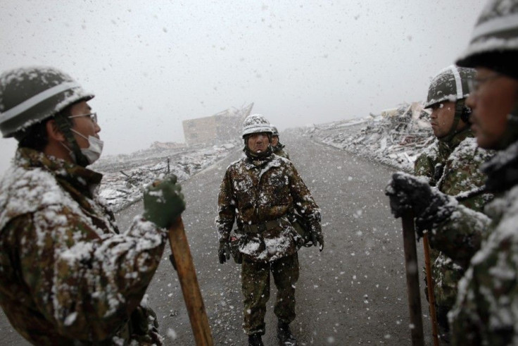 A Japan Self-Defense Force officer gives instruction to his team at the devastated residential area of Otsuchi as heavy snow falls
