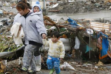 Family walks past rubble after the earthquake and tsunami in Minamisanriku City