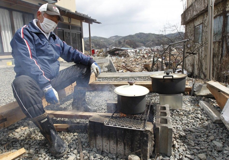 A man cooks at his home at a devastated area hit by the earthquake and tsunami in Kesennuma, north Japan, March 17, 2011. 
