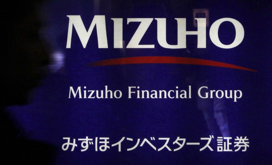 A man passes a logo of the Mizuho Financial Group in Tokyo