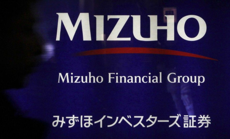 A man passes a logo of the Mizuho Financial Group in Tokyo