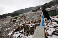 A survivor looks on at the debris from the second floor of his destroyed house in Yamada, Iwate Prefecture, days after the area was devastated by a magnitude 9.0 earthquake and tsunami, March 17, 2011