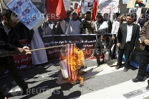 Demonstrators protesting the presence of the Saudi Arabian military in Bahrain burn a U.S. flag in Tehran.