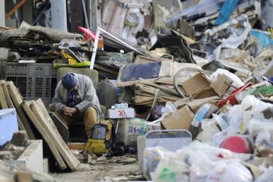 An elderly man sits on a chair among rubble in Kesennuma City