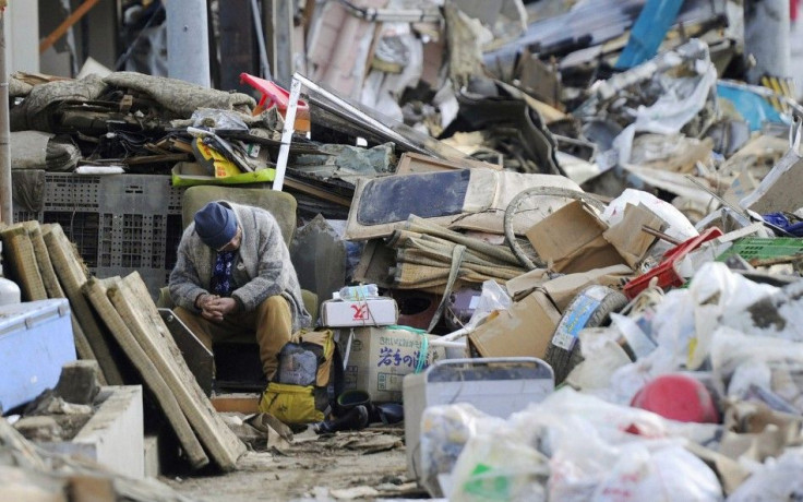 An elderly man sits on a chair among rubble in Kesennuma City