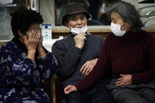 Elderly Japanese people are seen wearing face masks at a collective shelter for earthquake and tsunami survivors in Rikuzentakat