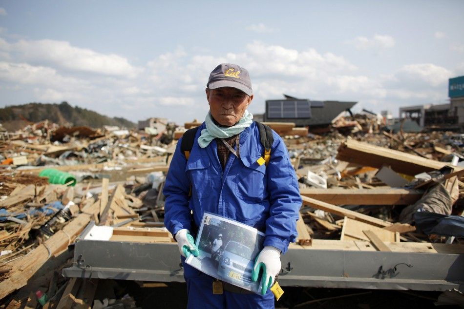 Shigemasa Kanno, 74, holds a photograph of his missing 68-year-old wife Sueko Kanno, at the debris of his destroyed house in Rikuzentakata