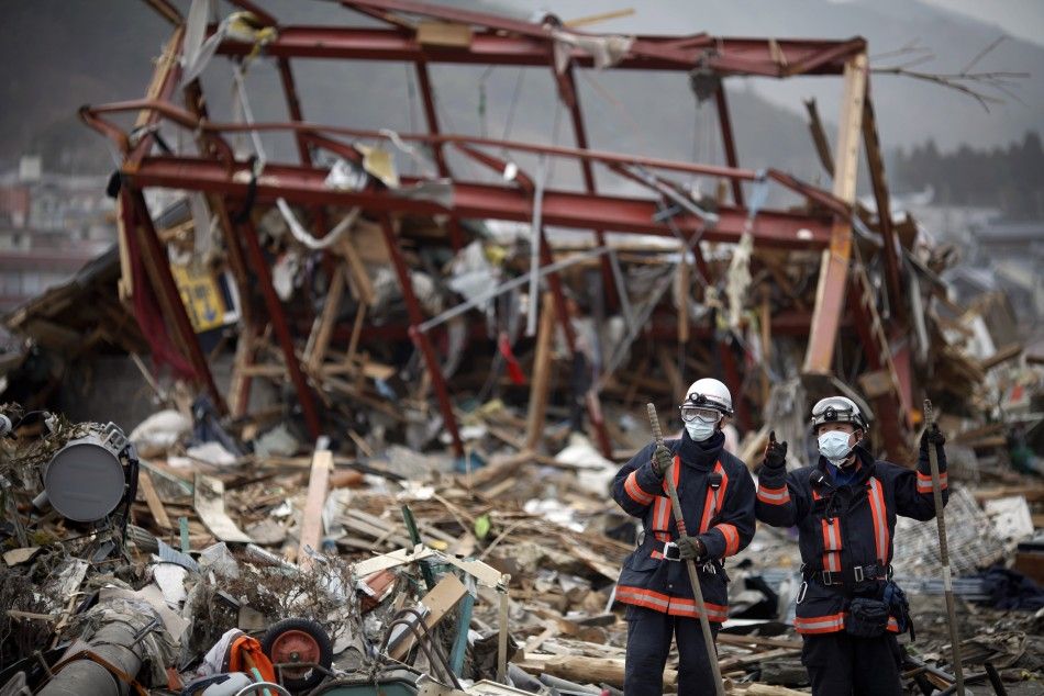 Japanese rescue workers pause from their operation in the destroyed residential part of Ofunato 
