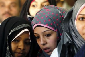 Women wait outside a polling center at a school during a national referendum in Cairo