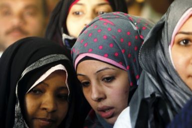 Women wait outside a polling center at a school during a national referendum in Cairo