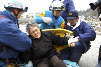 80-year-old Sumi Abe (C) is helped by emergency workers after being rescued from under the rubble in Ishinomaki City