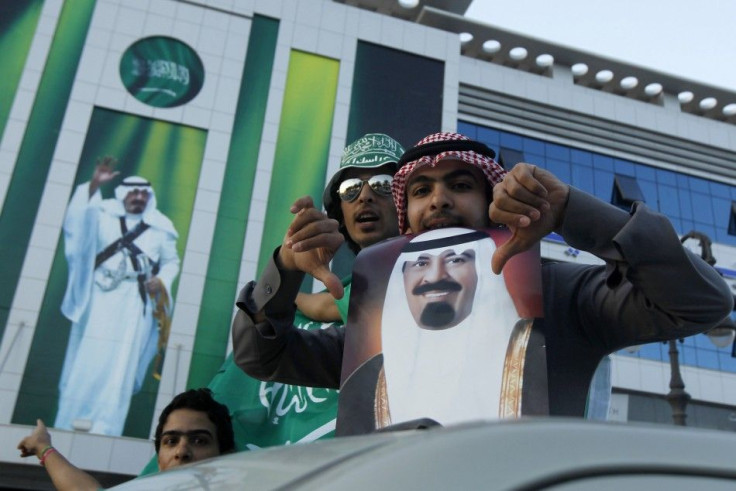 Men pose with a photograph of Saudi's King Abdullah after the King addressed the nation in Riyadh