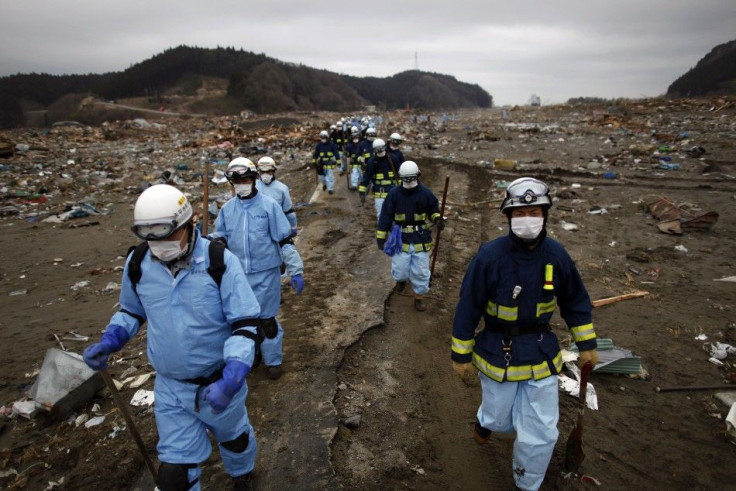 Rescue workers make their way through an area devastated by a tsunami as they search for victims in Rikuzentakata