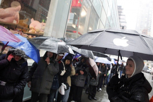 An employee (R) looks at customers stand in line outside Apple's flagship 5th Avenue store to purchase iPad 2 tablets in New York, March 16, 2011.