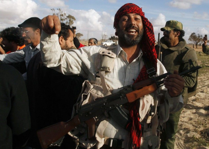 A rebel celebrates at the road between Benghazi and Ajdabiyah