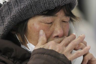 A woman cries as she talks with her relative on the phone at a temporary city hall office where people check the list of missing people and the dead in Kamaishi
