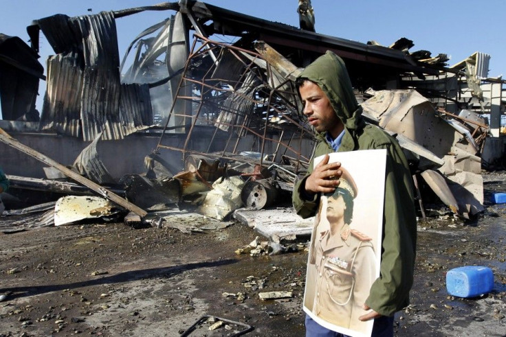 A Libyan holds a portrait of Libya's leader Muammar Gaddafi at a naval military facility damaged by coalition air strikes, in Tripoli