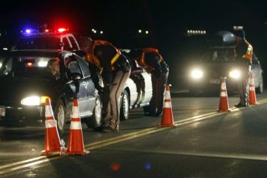 Officers ask drivers if they have been drinking while smelling for alcohol at a mobile DUI checkpoint 
