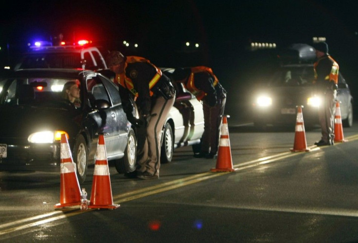 Officers ask drivers if they have been drinking while smelling for alcohol at a mobile DUI checkpoint 
