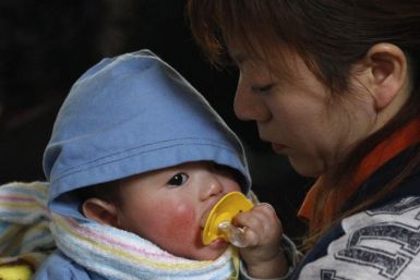 A woman holds her baby at a shelter for survivors at a village that was destroyed by an earthquake and tsunami in Yamada