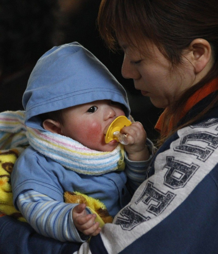 A woman holds her baby at a shelter for survivors at a village that was destroyed by an earthquake and tsunami in Yamada