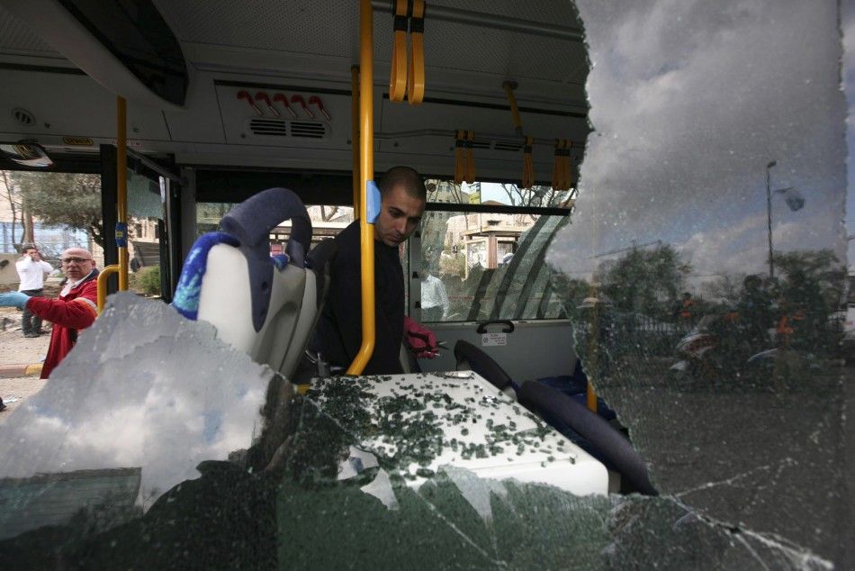 An Israeli police officer surveys the inside of a damaged bus at the scene of an explosion in Jerusalem