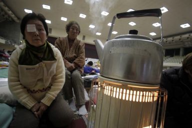 Suzuki and her friend Takahashi, who were evacuated from Minami Soma in Fukushima, sit next to a stove at an evacuation center in Yonezawa
