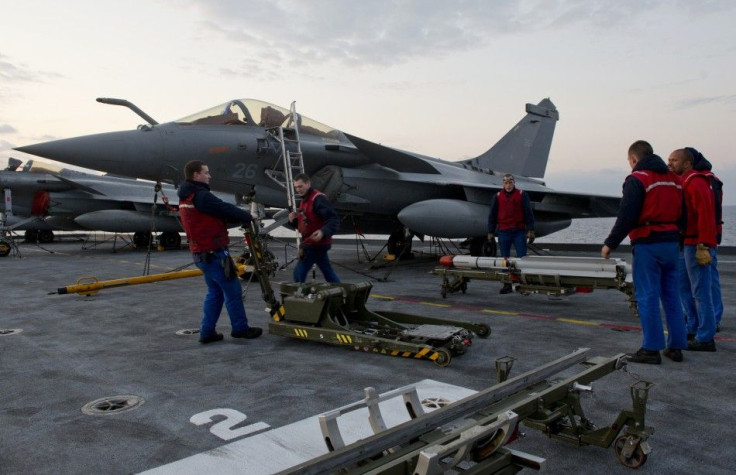 Sailors load a Mica missile under a Rafale fighter